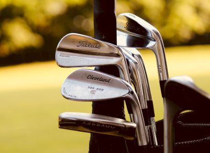 The image shows a set of golf clubs in a bag, with brands like Titleist and Cleveland visible on the clubs.