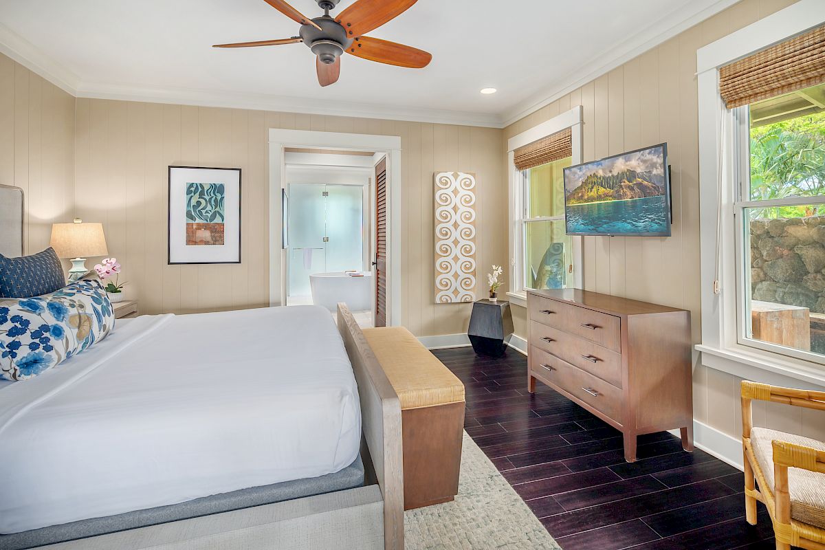 The image features a cozy bedroom with a bed, a dresser, TV, and natural light from the windows. It has a calming, modern design.