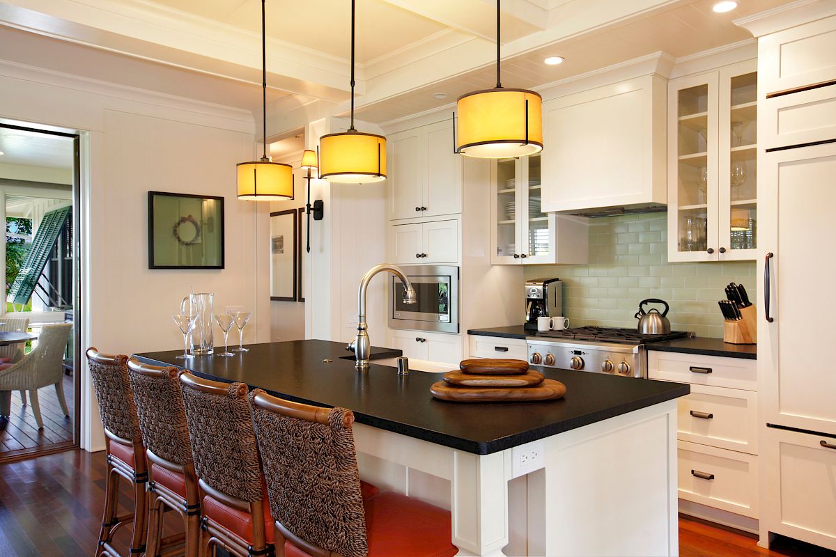 The image features a modern kitchen with white cabinetry, a dark countertop, pendant lights, and bar seating for four.